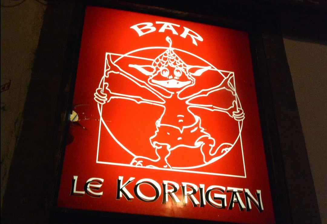 L’enseigne rouge lumineuse du bar Le Korrigan, avec son korrigan dessiné façon homme de Vitruve